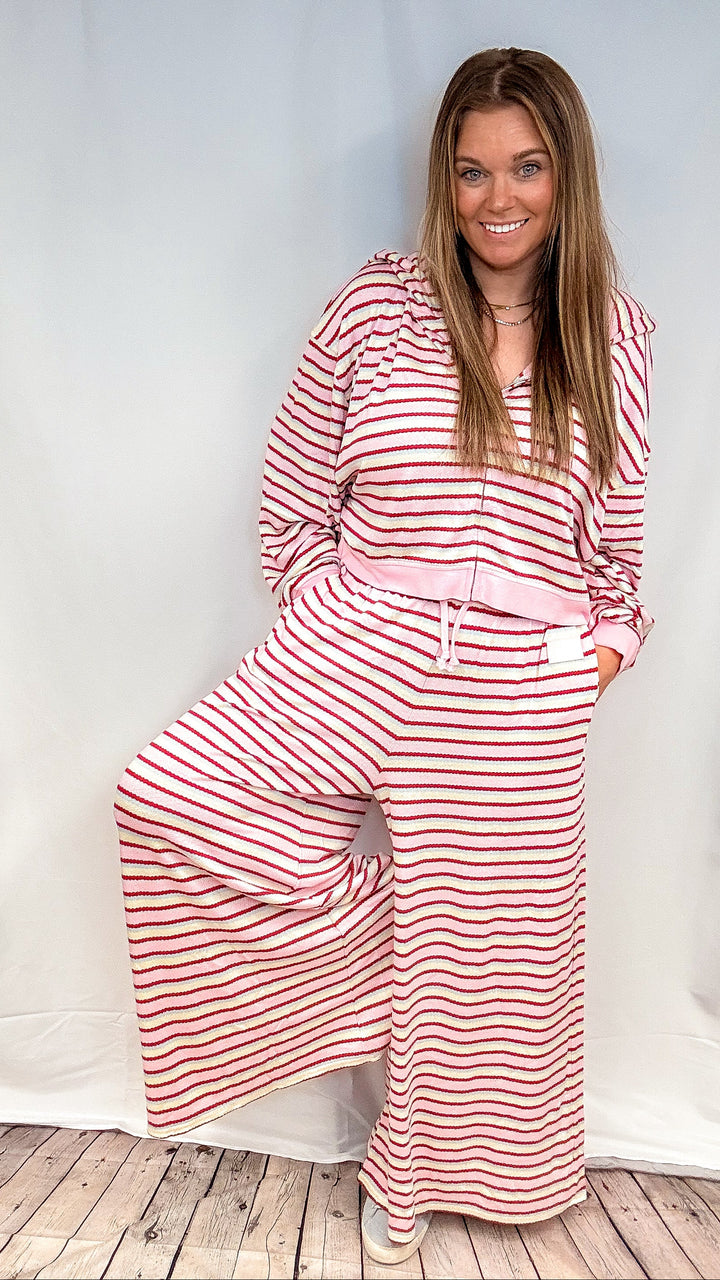 Woman wearing matching pink, maroon, yellow and blue stripe set on white background