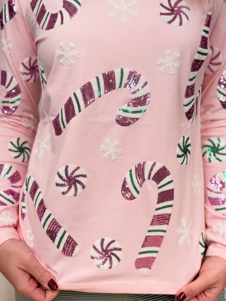 Close up of pink long sleeve top with sequin candy canes and candies