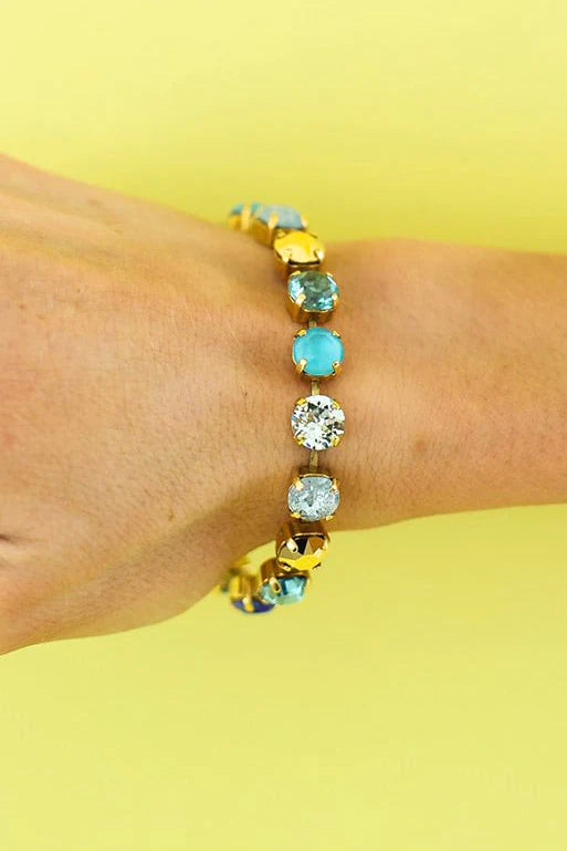 Arm wearing blue multi color Swarovski Crystal bracelet on plain background