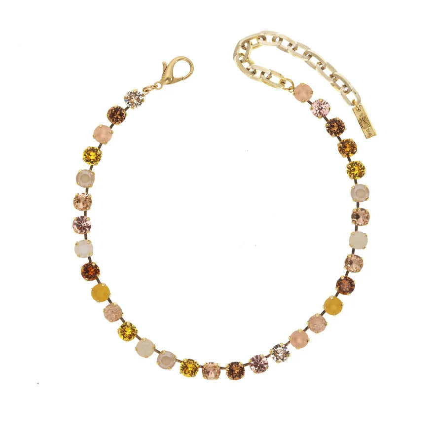 Gold necklace with neutral color swarovski crystals on plain background
