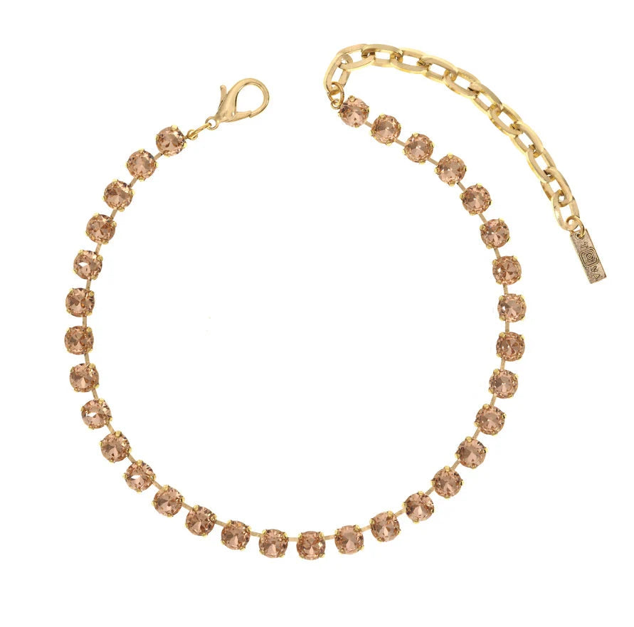 Gold necklace with champagne colored Swarovski Crystals on plain background