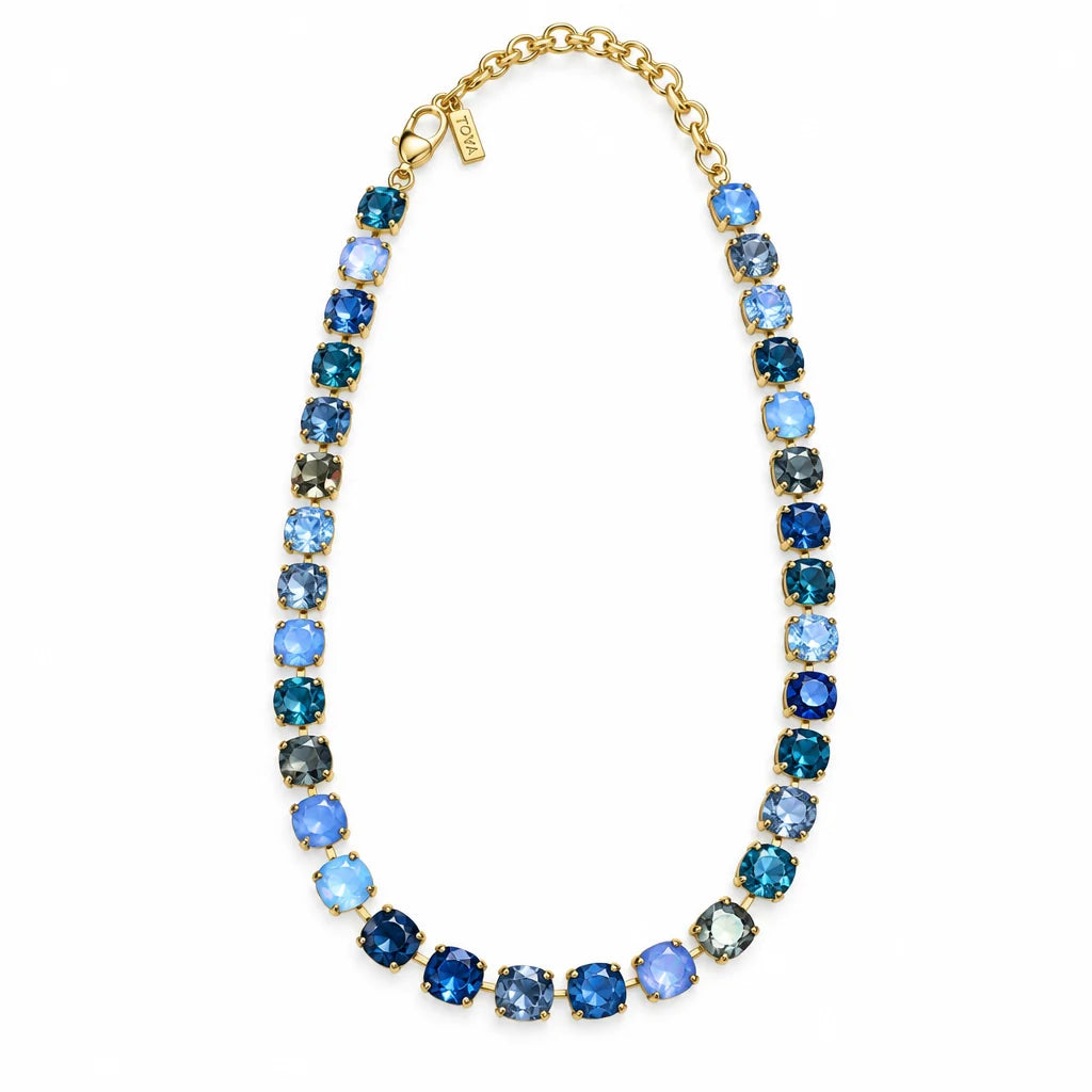 Gold necklace with multicolor blue Swarovski Crystals on plain background