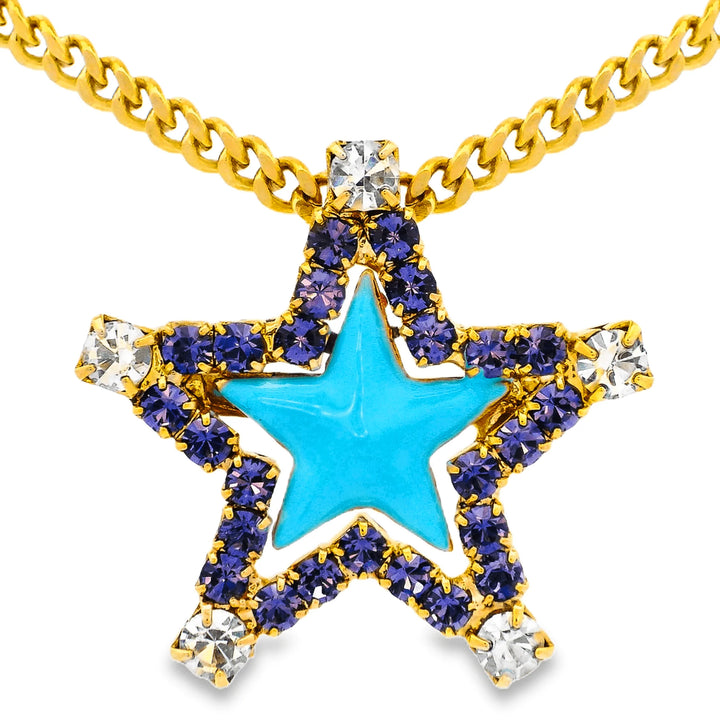 A gold star-shaped pendant necklace featuring a bright turquoise blue center, surrounded by rows of deep purple rhinestones and clear crystal accents, suspended from a gold curb chain against a white background.