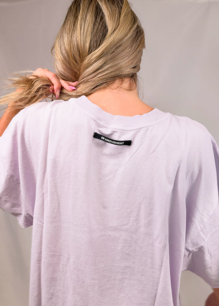 Woman shown from back wearing purple tee with &