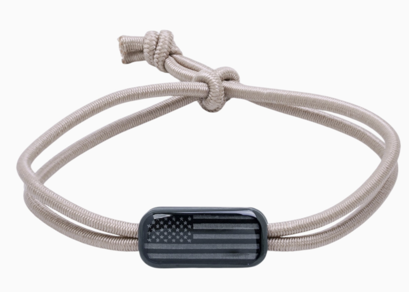 Tan cord bracelet with black flag clay tag on white background