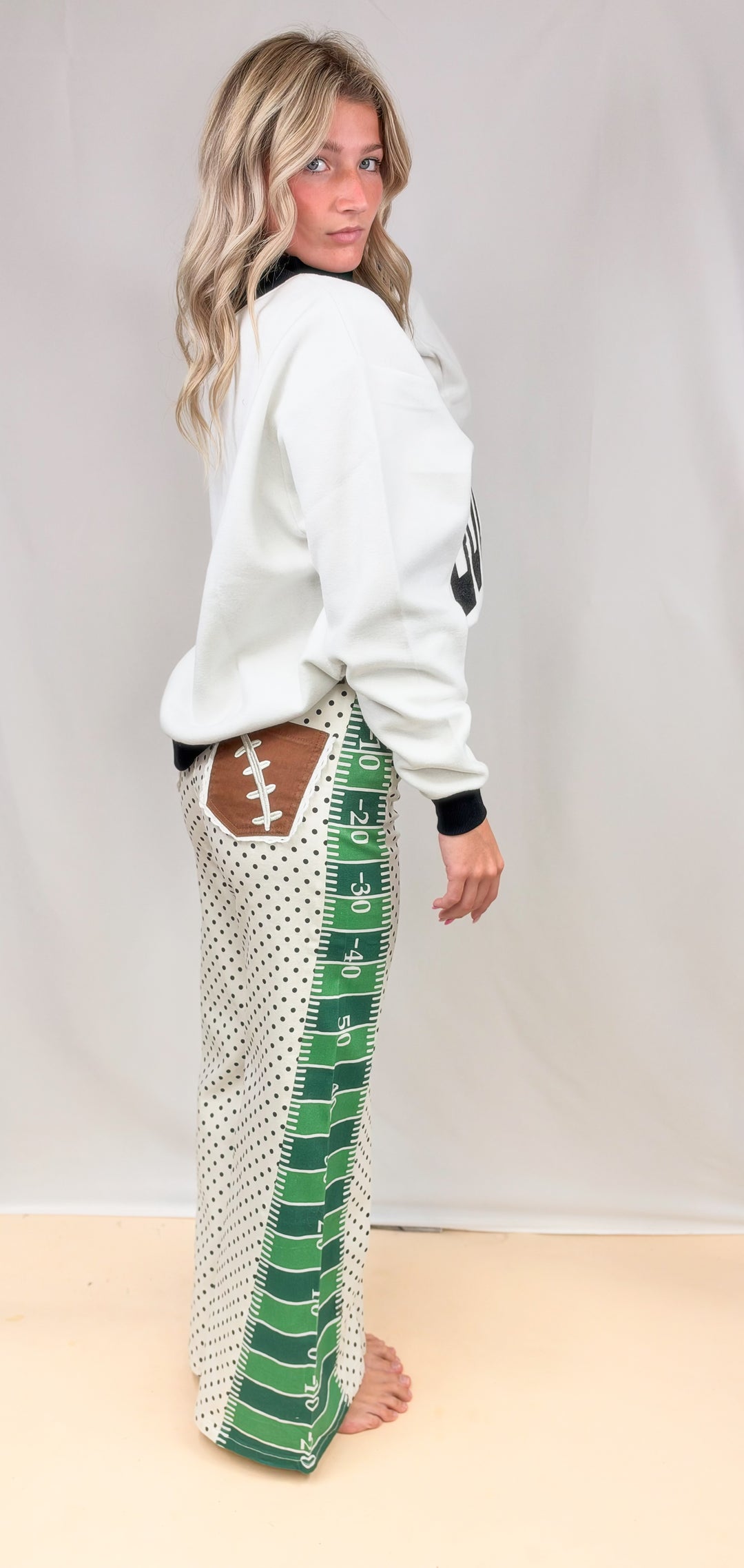 Woman wearing black and white mock neck with football field detail pants on plain background