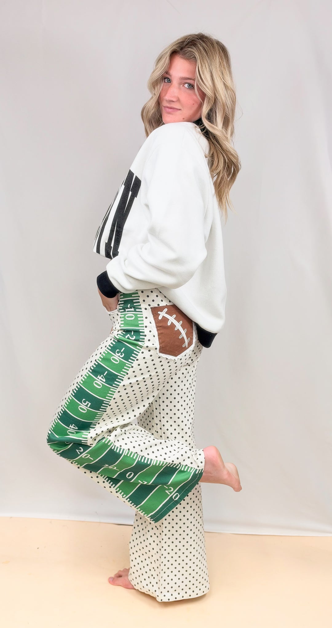Woman wearing black and white mock neck with football field detail pants on plain background