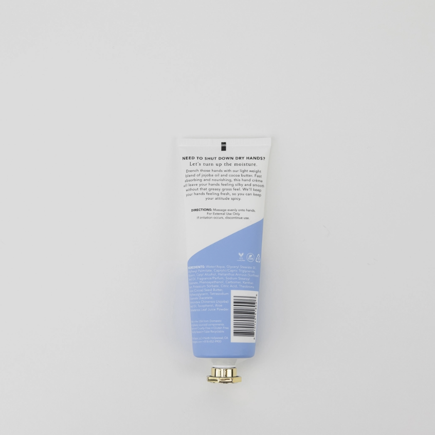 The back of a white and light blue squeeze tube of toothpaste is shown against a light gray background, with a small gold cap placed below it.