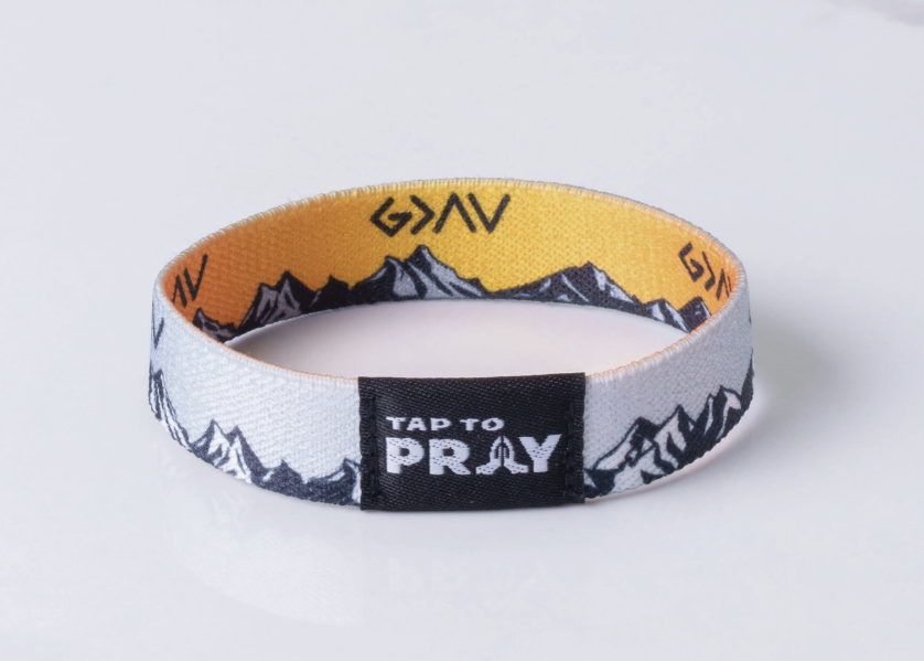 A fabric wristband with a yellow interior, black and white mountain graphics, and a black center tab that reads &