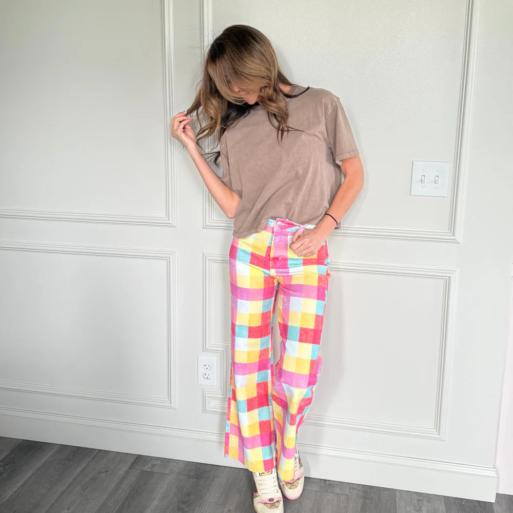 woman wearing plaid pants and brown shirt on plain background