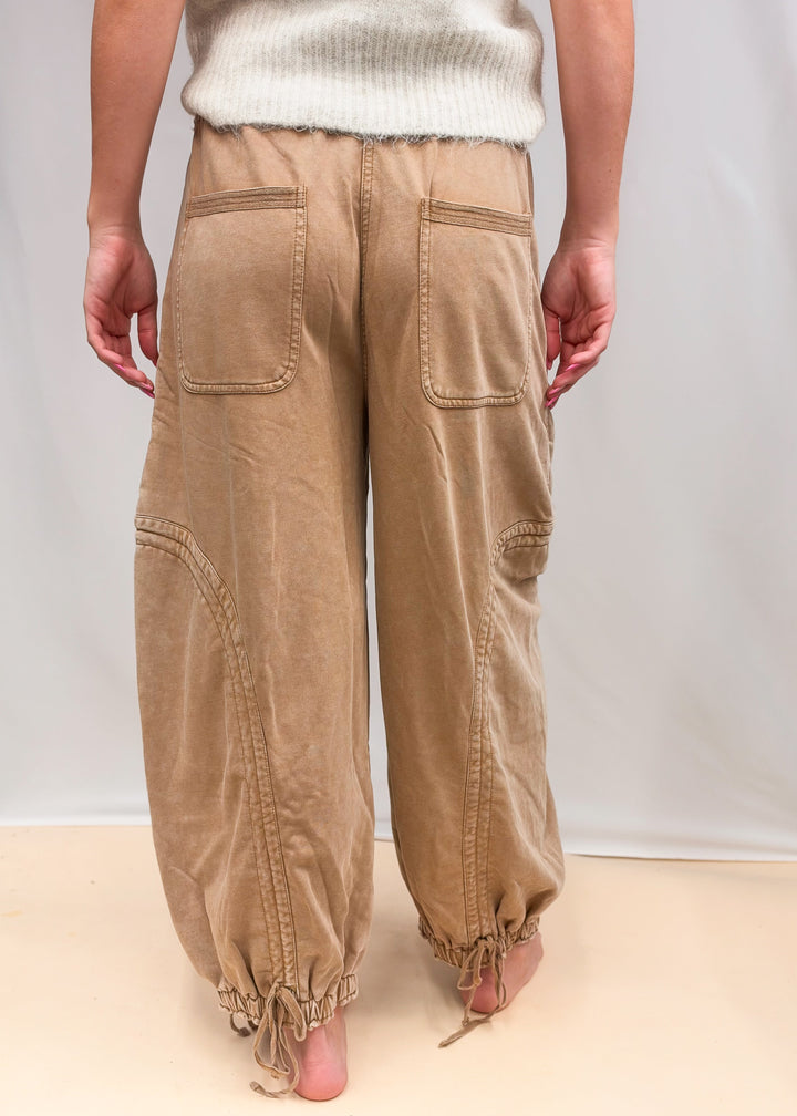 Woman shown from back wearing camel color sweatpants and cream top on plain background