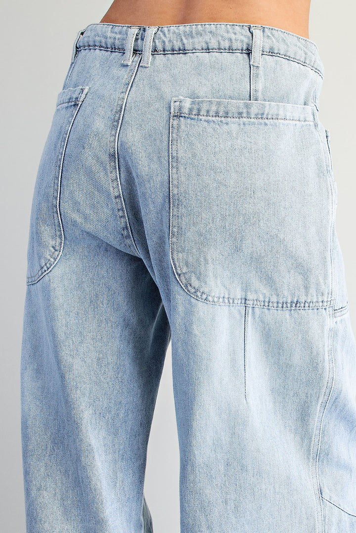 Close-up back view of a person wearing light-wash blue denim jeans, showing the waistband, belt loops, and back pocket details.