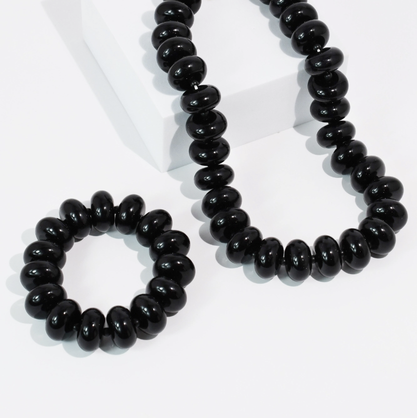 Black beaded necklace and bracelet sitting on white background