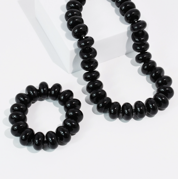 Black beaded necklace and bracelet sitting on white background
