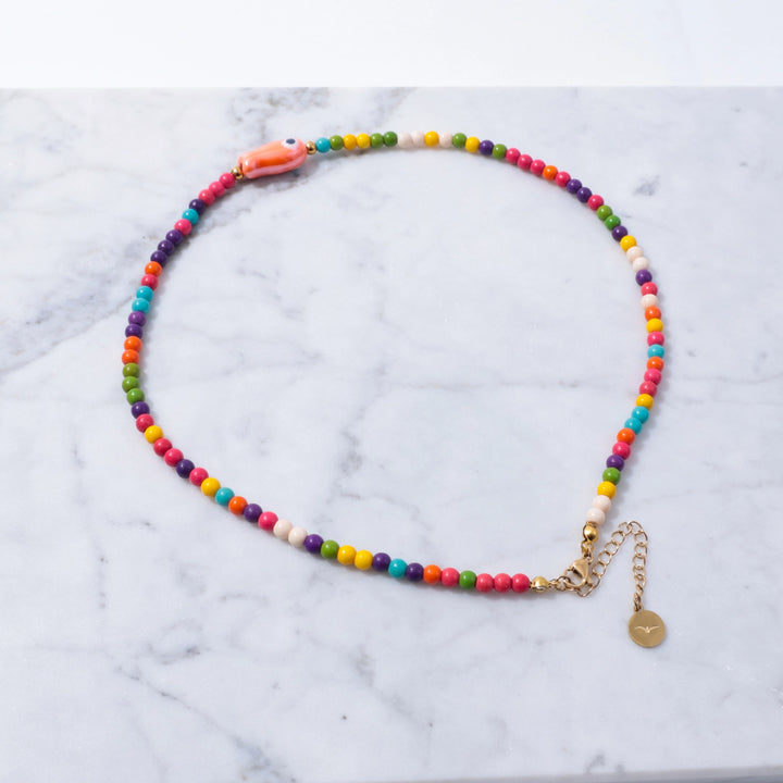 Colorful beaded necklace with a gold chain on a marble background