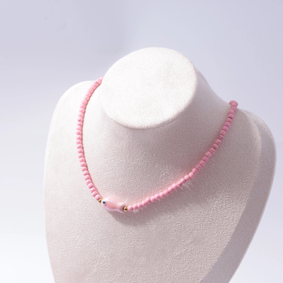 Pink beaded necklace on a white mannequin bust against a light gray background