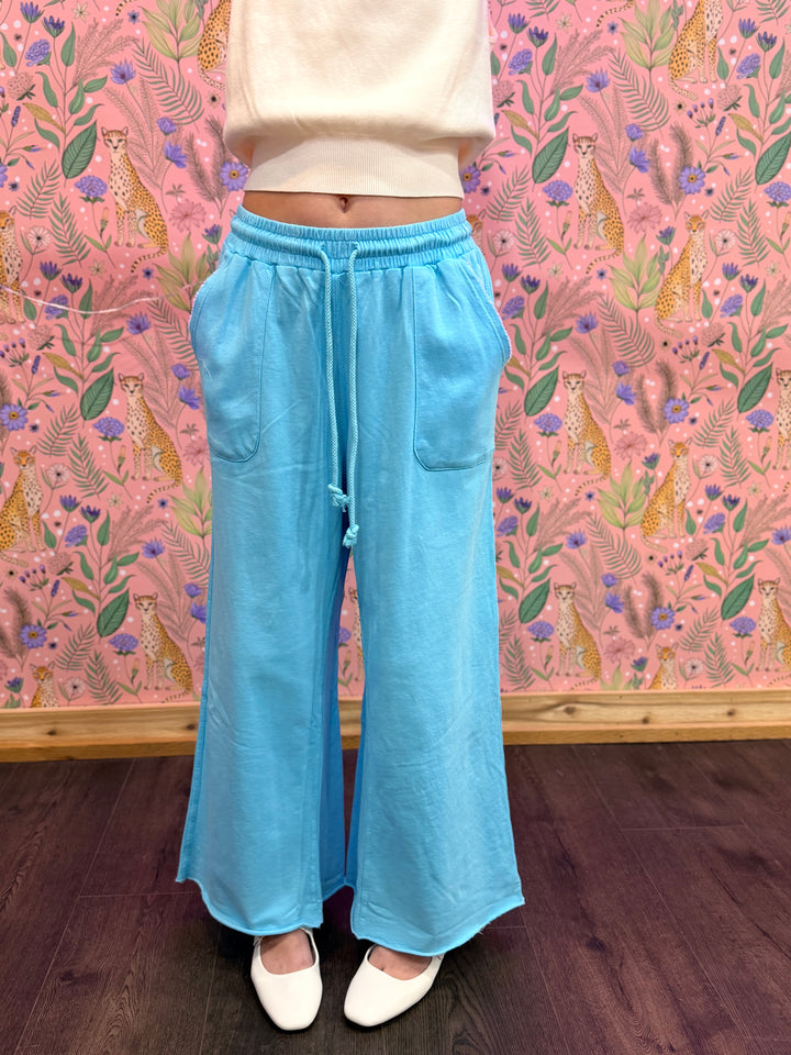 Person wearing blue pants and white shoes in from of colorful background