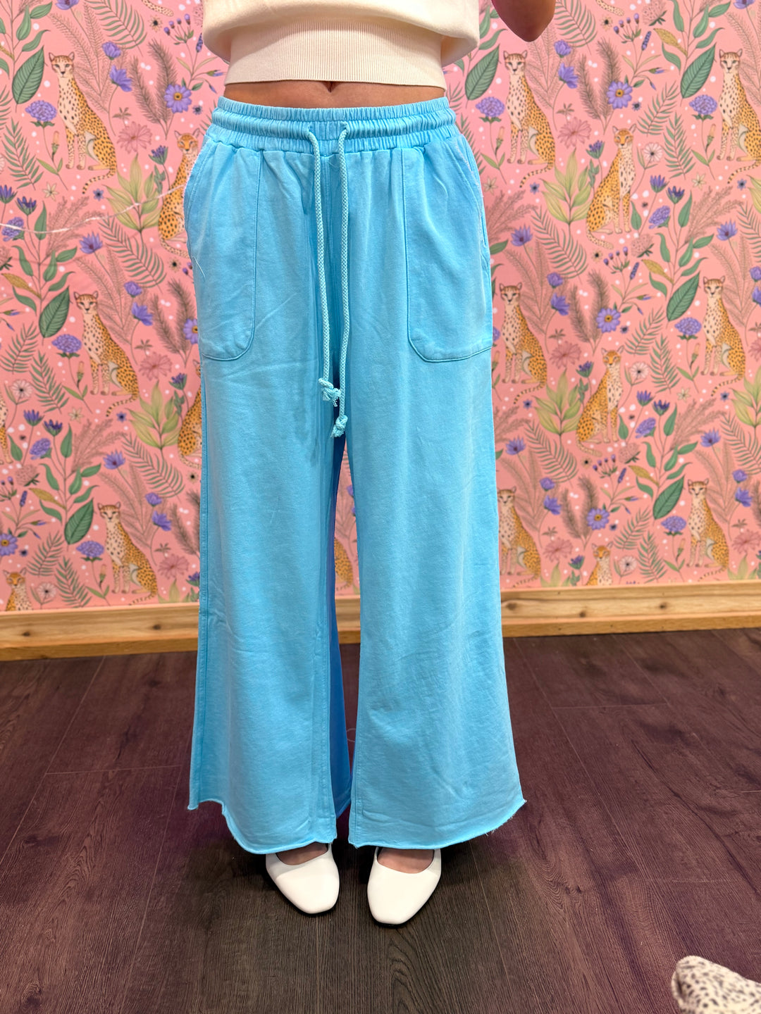 Person wearing light blue pants with a patterned pink wall in the background
