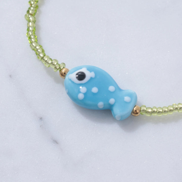 Necklace with a blue fish-shaped charm on a light background