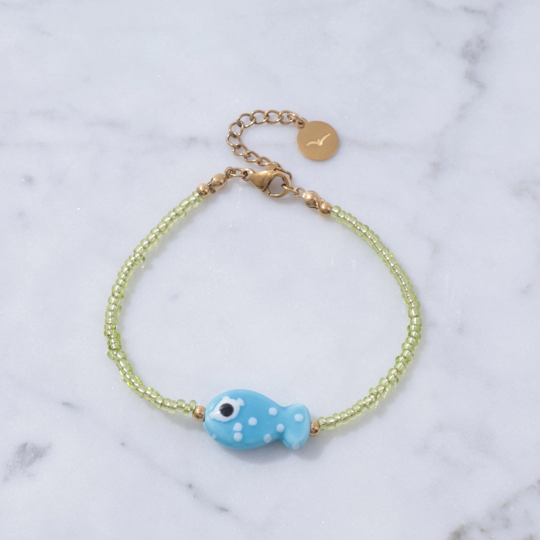 Bracelet with a blue fish charm on a marble background