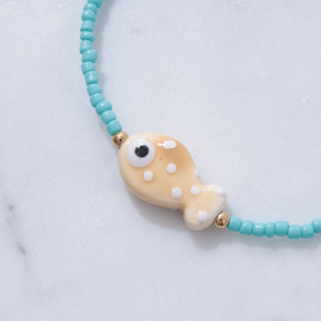 Bracelet with a fish-shaped charm on a light blue background