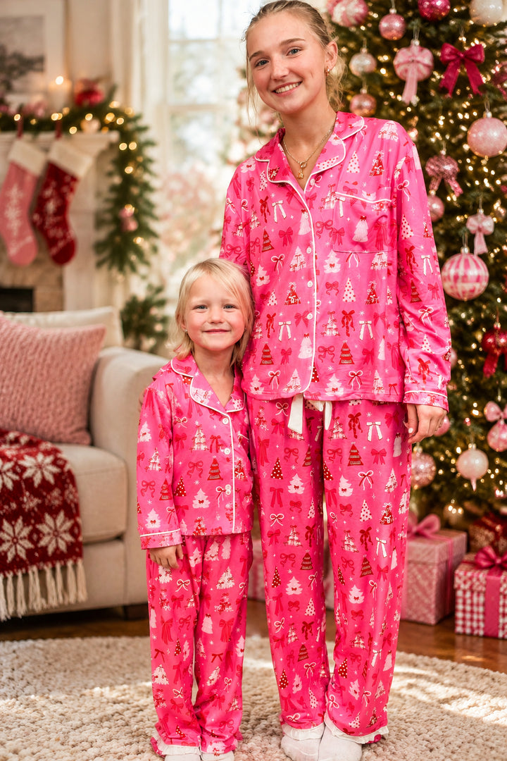 Two girls wearing matching christmas pajamas on plain background