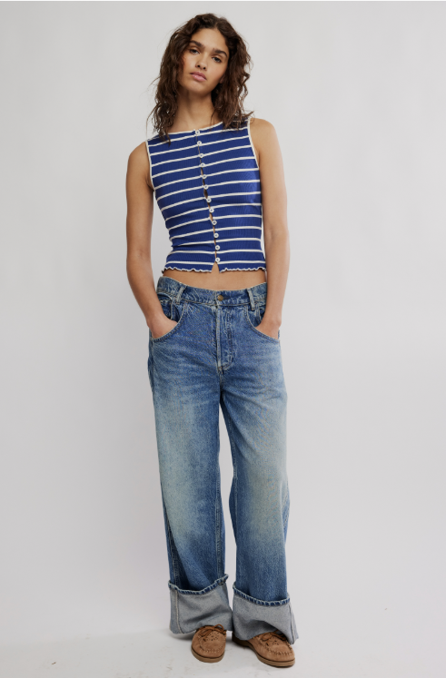 Woman wearing a blue striped top and jeans on a plain background