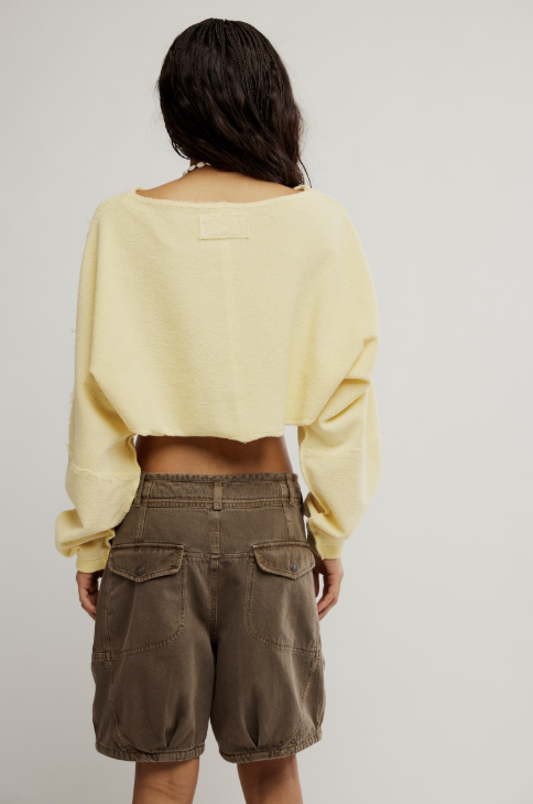 Person wearing a yellow sweater and brown shorts on a plain background