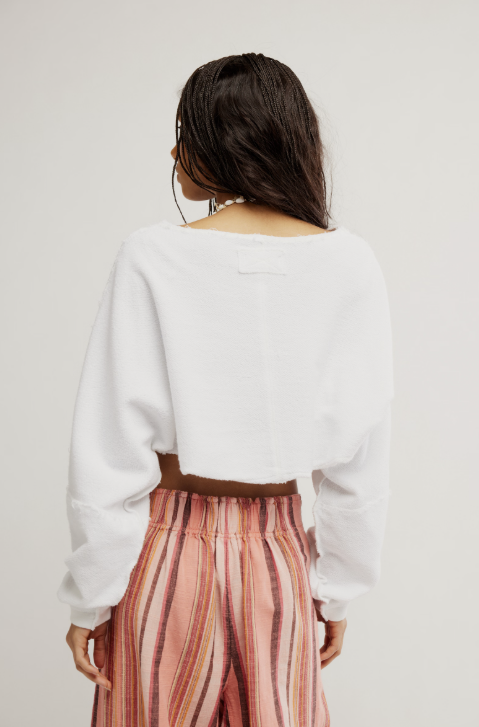 Person wearing a white sweater and striped pants on a plain background