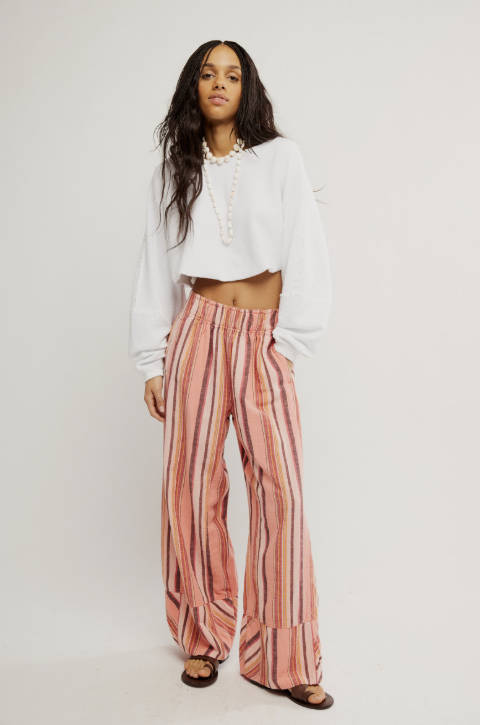 Woman wearing a white cropped top and pink striped pants on a white background