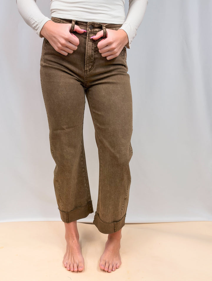 Woman wearing brown jeans on plain background