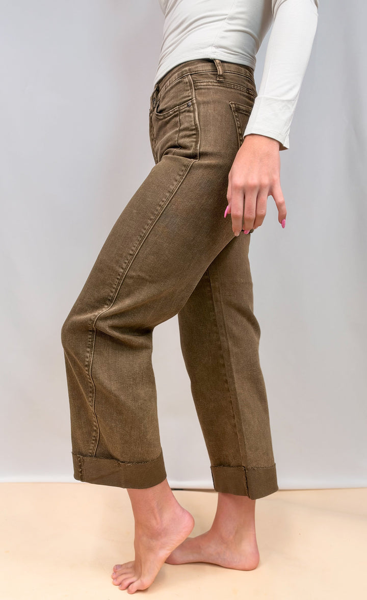 Woman shown from side view wearing brown jeans on plain background