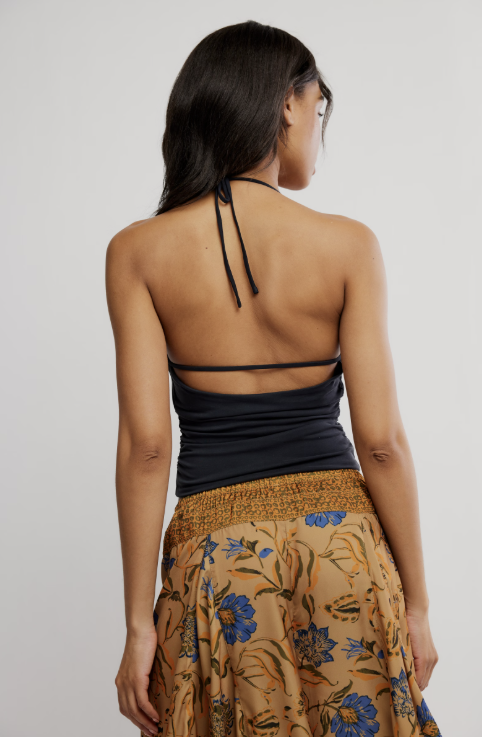 Woman wearing a black halter top and floral skirt on a plain background