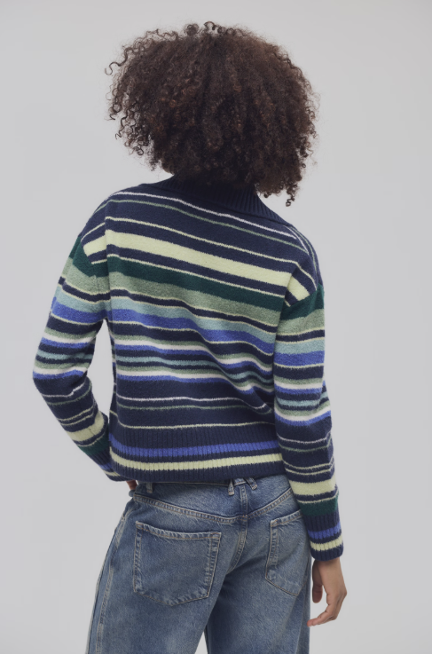 A person shown from the back wearing a striped knit sweater and blue jeans against a plain light gray studio background.