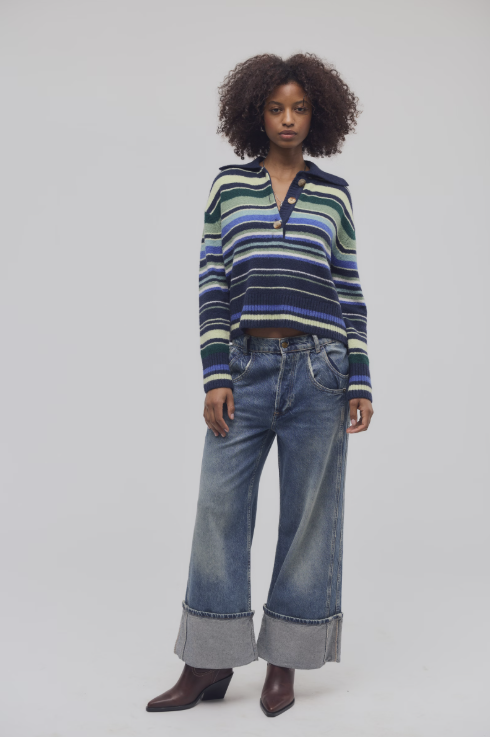 Woman wearing blue and green stripe sweater and jeans on white background