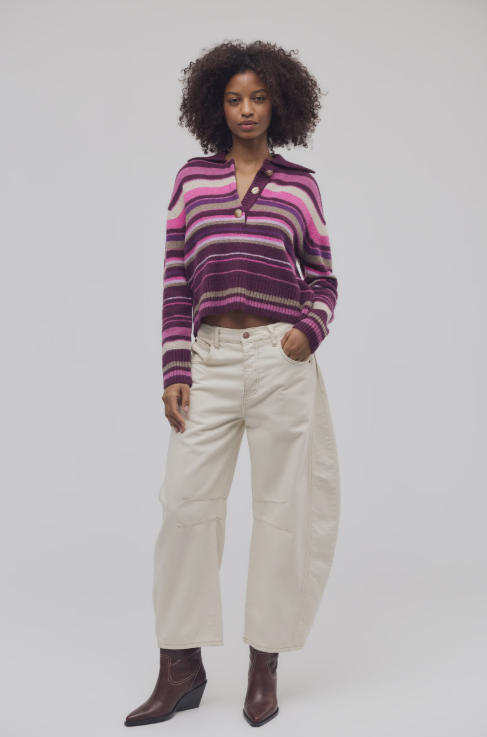 Woman wearing purple and pink stripe sweater and ecru jeans on white background
