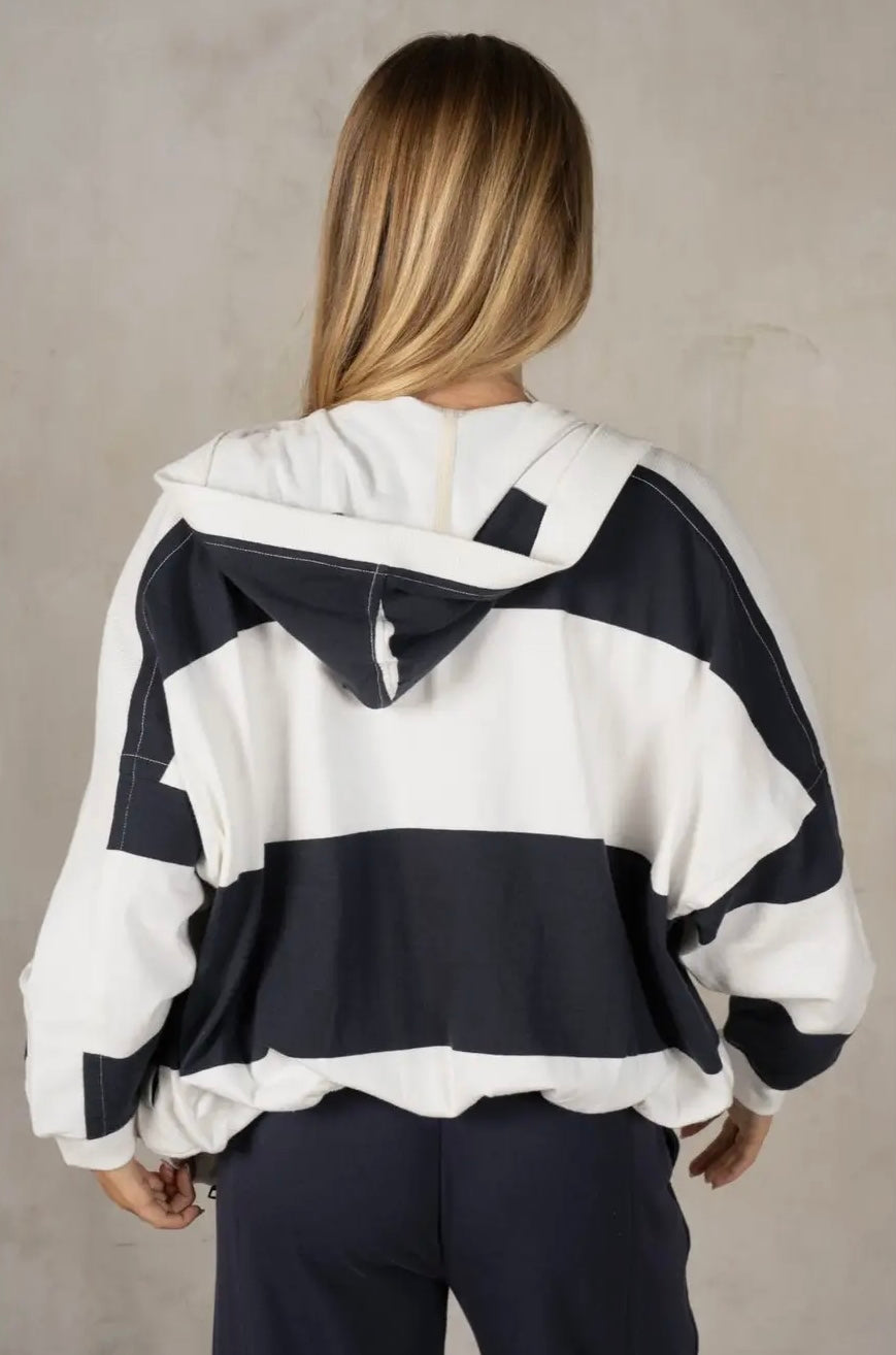 Person wearing a navy and white striped hoodie against a plain background