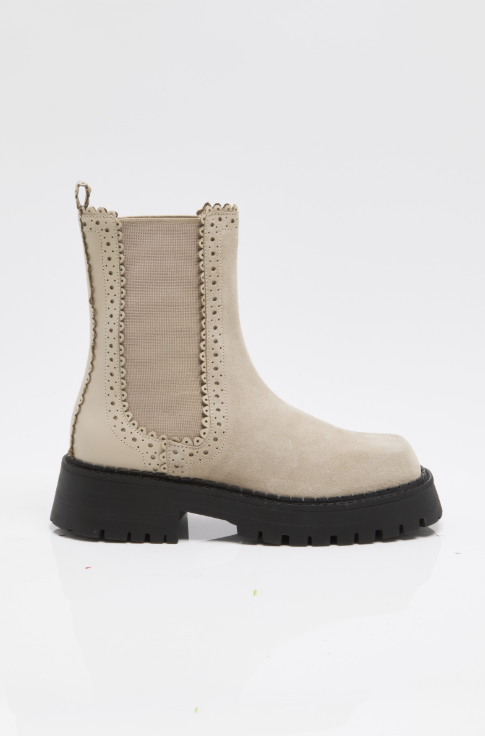 A single beige ankle boot with a black lug sole and a textured elastic side panel, shown in profile against a white background.