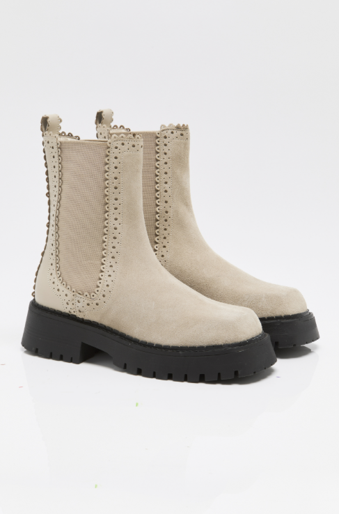 A pair of beige suede Chelsea-style ankle boots with black platform soles and decorative perforated trim, photographed on a clean white studio background.