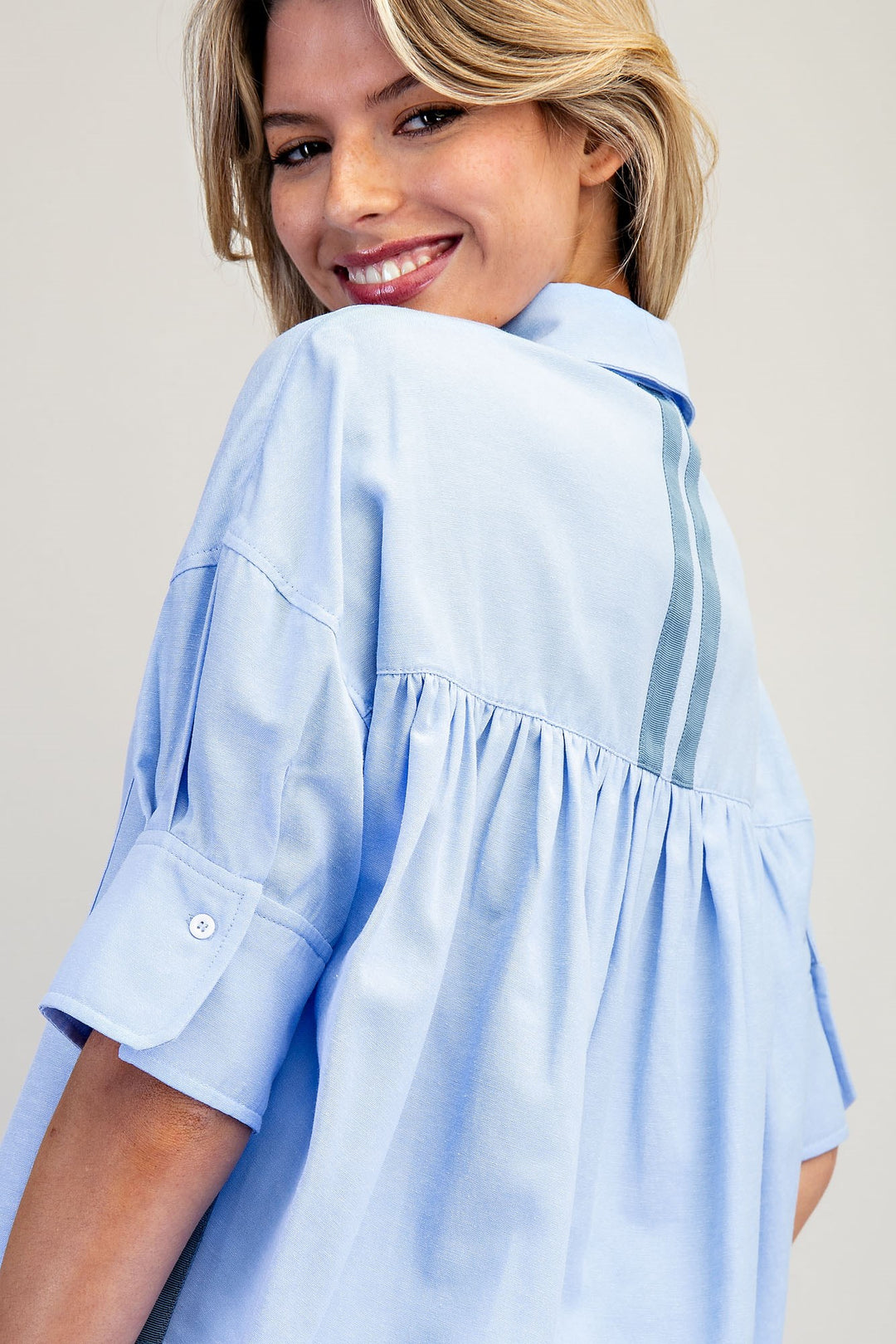 Woman wearing a light blue blouse against a plain background