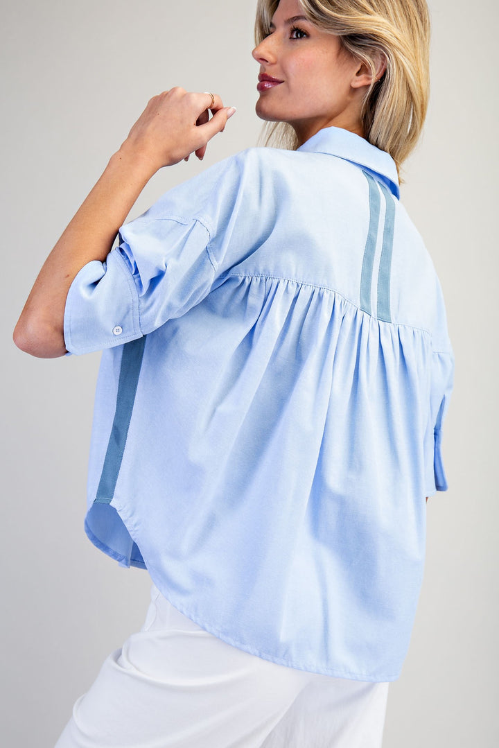 Woman wearing a light blue blouse against a plain background