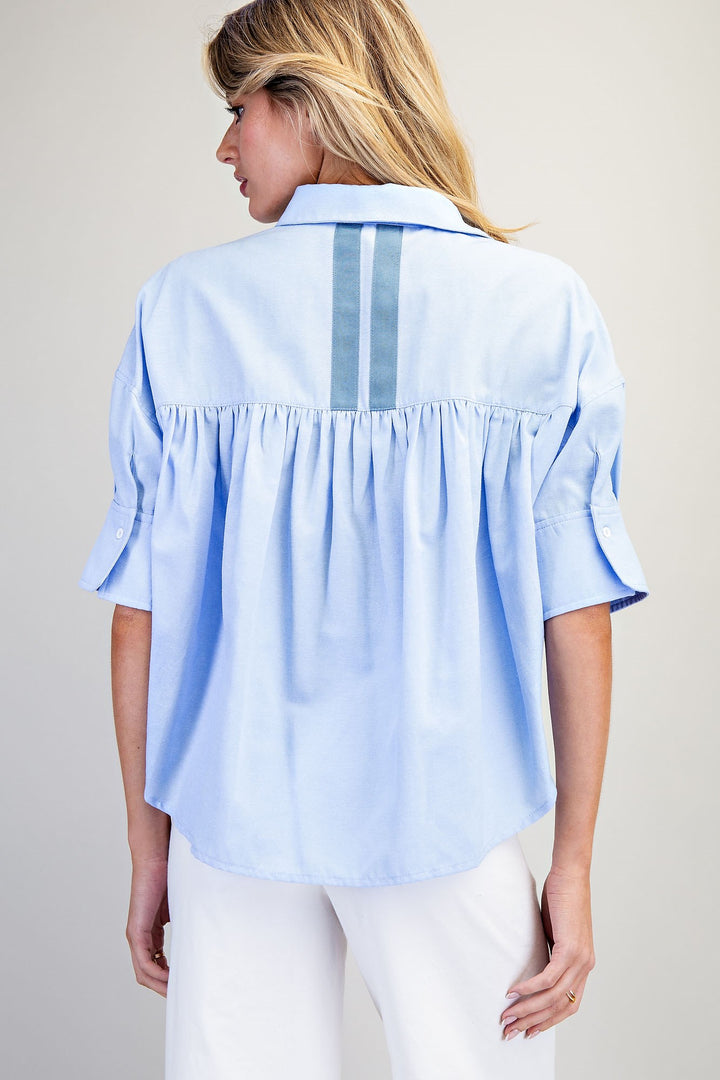 Woman wearing a light blue button-up shirt with a white background