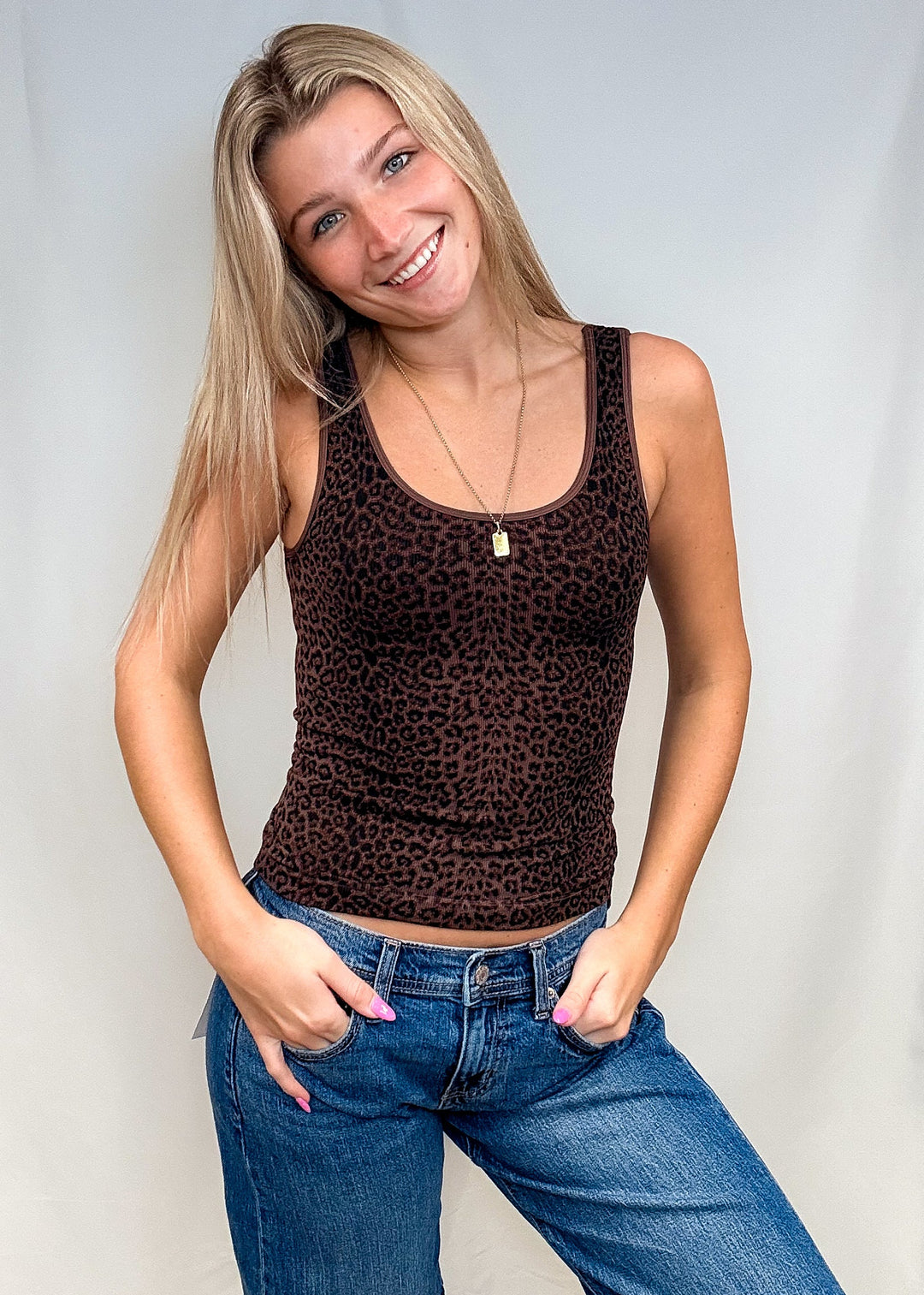 Woman wearing brown leopard print tank top with blue jeans on white background