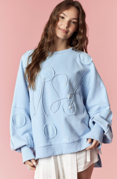 Woman wearing light blue pullover and white skirt on pink background