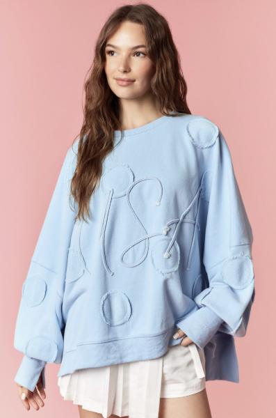 Woman wearing light blue pullover and white skirt on pink background