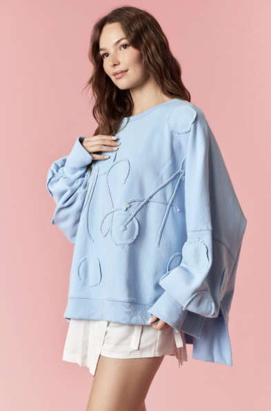 Woman wearing light blue pullover and white skirt on pink background