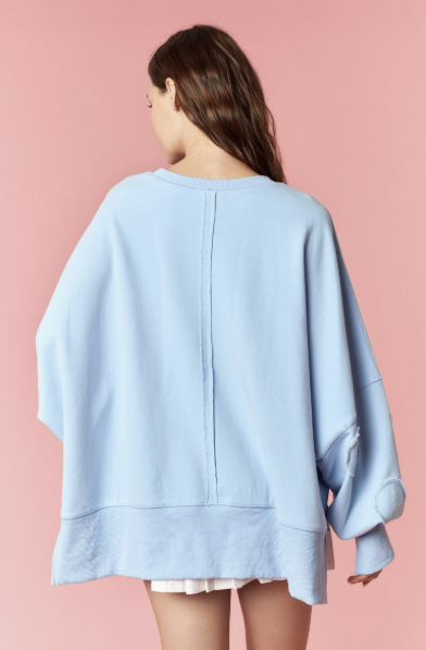 Woman wearing light blue pullover and white skirt on pink background