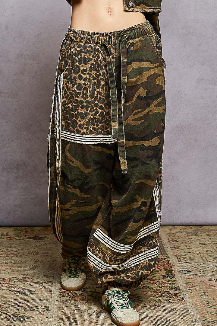 Camouflage and leopard print pants on a textured floor with a gray background