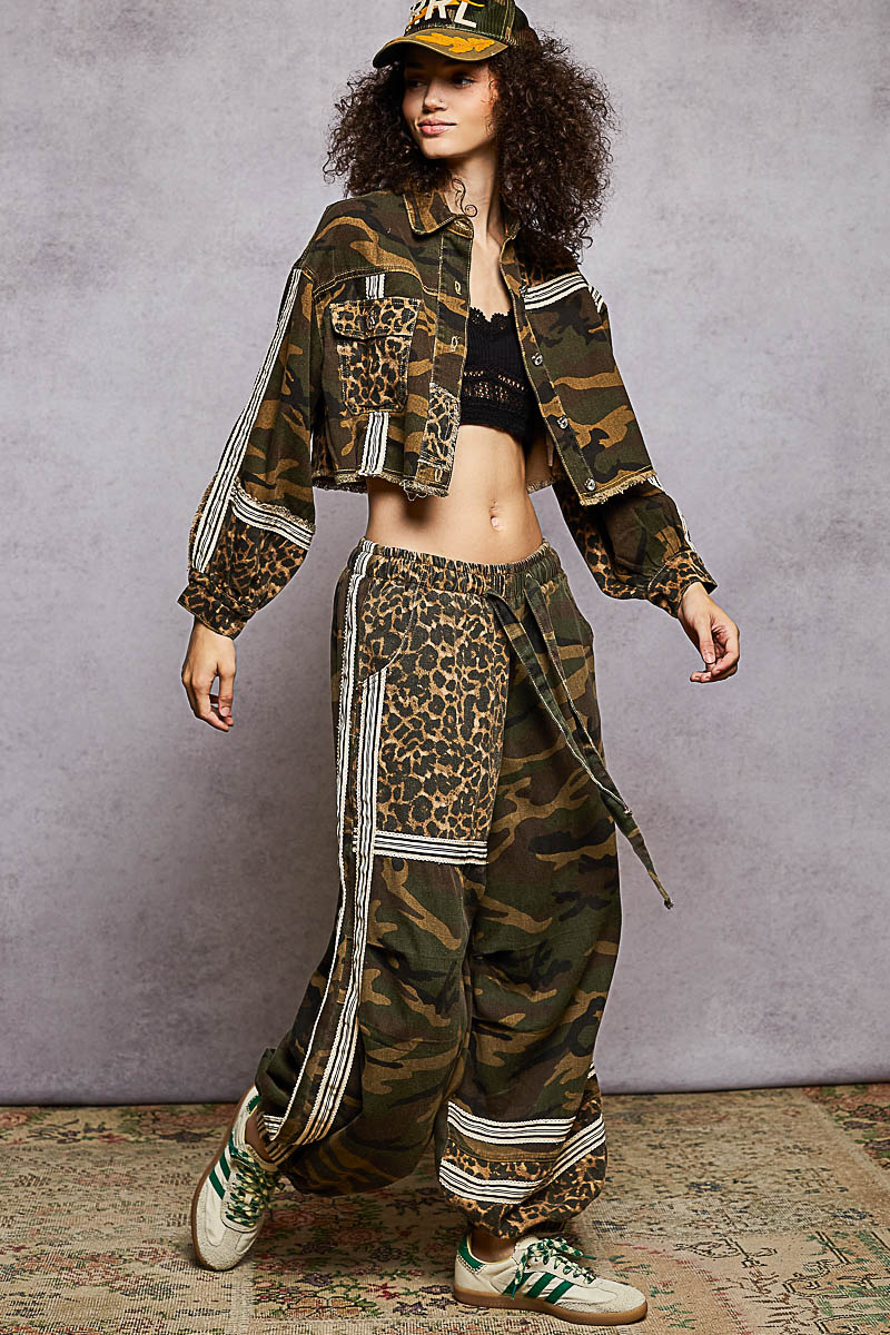 Person wearing a camouflage jacket and leopard print pants with a gray background