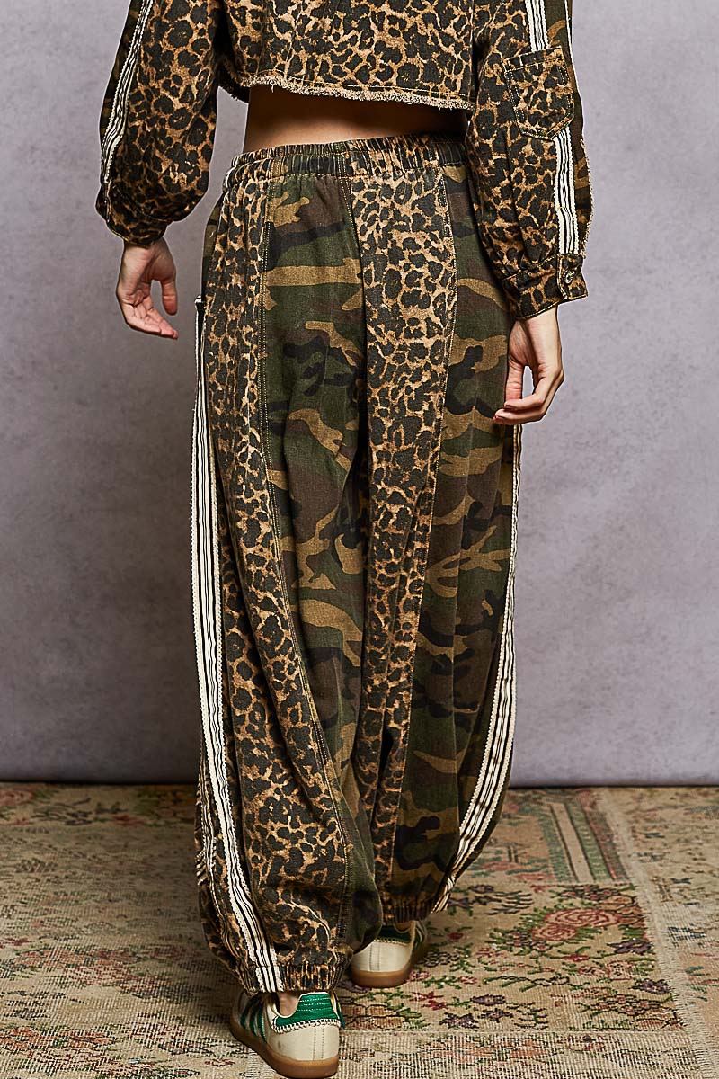 Person wearing a leopard print top and camouflage pants with white stripes on a textured floor.